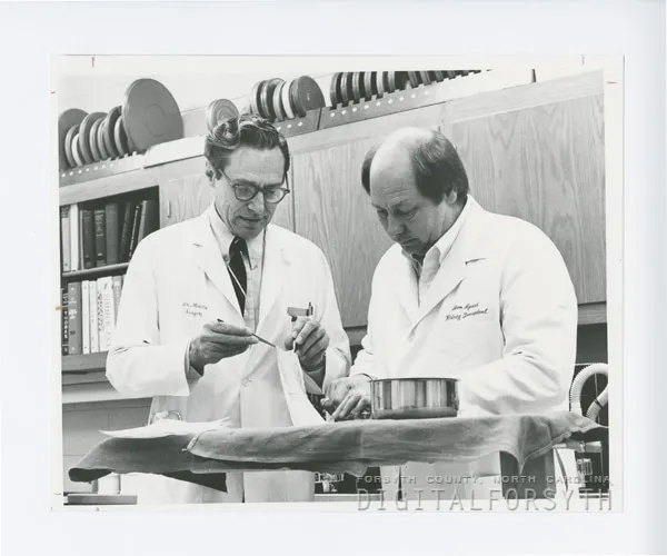 Dr. Jesse Meredith, Professor of Surgery and Director of the Burn Unit, and Don Lysell prepare skin for use in dressing burn wounds at North Carolina Baptist Hospital. The burn unit completed its first operating year in 1980. (Wake Forest University photo, part of Digital Forsyth collection.)